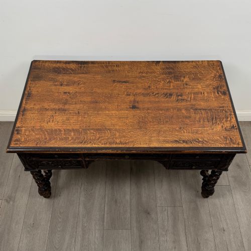 fig 8. A 19th-century dark oak writing table featuring carved drawer fronts, barley twist legs, and a low spiral stretcher.