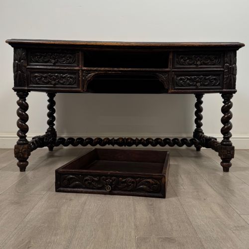 fig 9. A 19th-century dark oak writing table featuring carved drawer fronts, barley twist legs, and a low spiral stretcher.