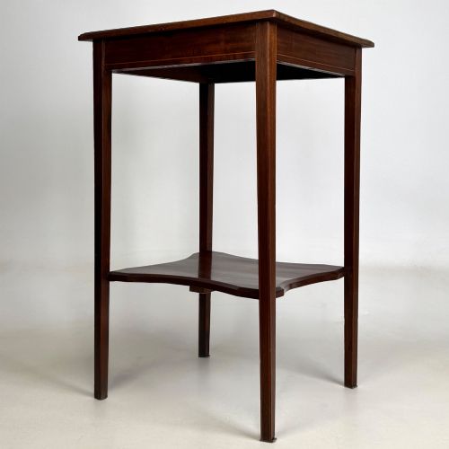 fig 1. A tall Edwardian mahogany side table featuring four slender tapered legs, a square top surface, and a concave-shaped lower undertier.