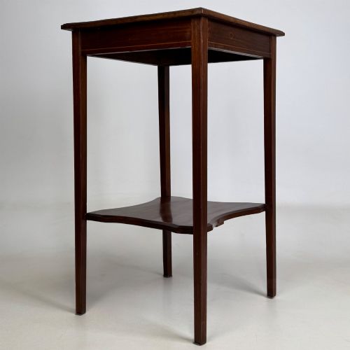 fig 3. A tall Edwardian mahogany side table featuring four slender tapered legs, a square top surface, and a concave-shaped lower undertier.