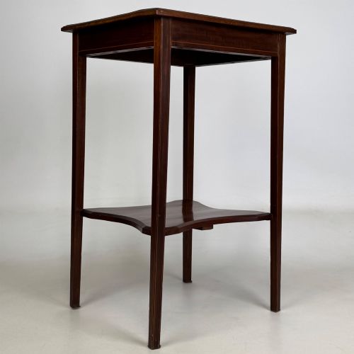 fig 7. A tall Edwardian mahogany side table featuring four slender tapered legs, a square top surface, and a concave-shaped lower undertier.
