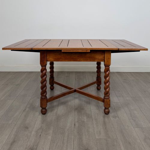 fig 1. An Edwardian warm oak draw leaf dining table featuring extended side leaves, barley twist legs, and an X-frame cross stretcher.
