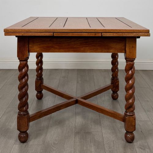 fig 2. An Edwardian warm oak draw leaf dining table featuring extended side leaves, barley twist legs, and an X-frame cross stretcher.