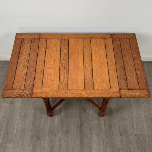 fig 4. An Edwardian warm oak draw leaf dining table featuring extended side leaves, barley twist legs, and an X-frame cross stretcher.