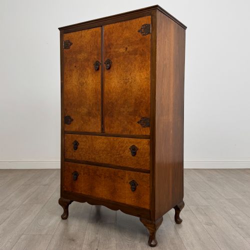 fig 2. An Edwardian burr walnut storage cupboard featuring two top doors with brass strap hinges above two drawers on cabriole legs.