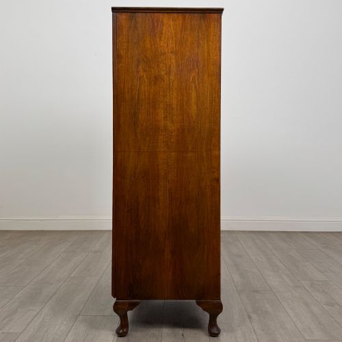 fig 7. An Edwardian burr walnut storage cupboard featuring two top doors with brass strap hinges above two drawers on cabriole legs.