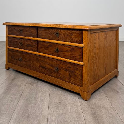 fig 1. A low 20th-century oak chest of drawers featuring five drawers arranged across three tiers with diamond-shaped metal handles.