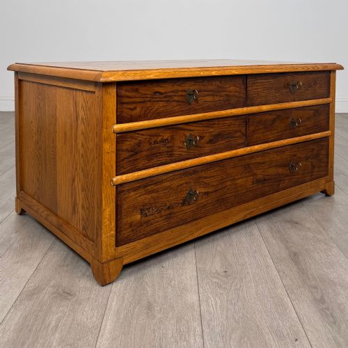 fig 7. A low 20th-century oak chest of drawers featuring five drawers arranged across three tiers with diamond-shaped metal handles.