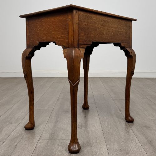 fig 3. An 18th-century Georgian oak side table featuring a single drawer with geometric inlaid border, lion mask brass ring handles, shaped apron, and four cabriole legs ending in pad feet.