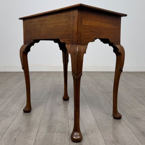 fig 5. An 18th-century Georgian oak side table featuring a single drawer with geometric inlaid border, lion mask brass ring handles, shaped apron, and four cabriole legs ending in pad feet.