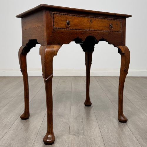 fig 7. An 18th-century Georgian oak side table featuring a single drawer with geometric inlaid border, lion mask brass ring handles, shaped apron, and four cabriole legs ending in pad feet.