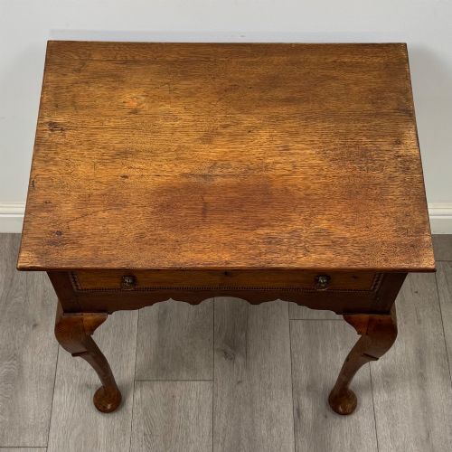 fig 8. An 18th-century Georgian oak side table featuring a single drawer with geometric inlaid border, lion mask brass ring handles, shaped apron, and four cabriole legs ending in pad feet.