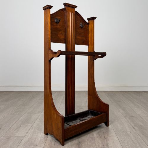 fig 7. An Edwardian walnut hall stand featuring a fluted central column, metal coat hooks, a horizontal umbrella rail, and a metal drip tray at the base.