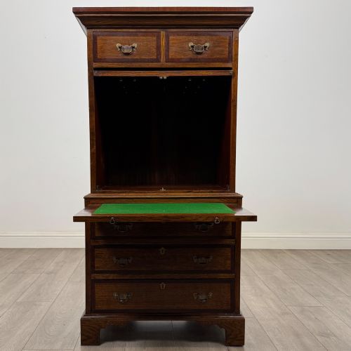fig 1. A tall early 20th-century oak chest on chest featuring multiple drawers with crossbanded borders and brass drop handles set on bracket feet.