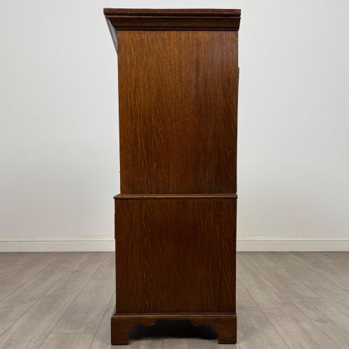 fig 3. A tall early 20th-century oak chest on chest featuring multiple drawers with crossbanded borders and brass drop handles set on bracket feet.