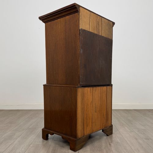 fig 4. A tall early 20th-century oak chest on chest featuring multiple drawers with crossbanded borders and brass drop handles set on bracket feet.