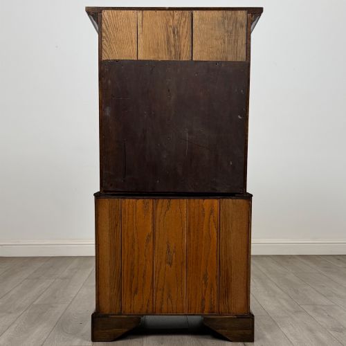 fig 5. A tall early 20th-century oak chest on chest featuring multiple drawers with crossbanded borders and brass drop handles set on bracket feet.
