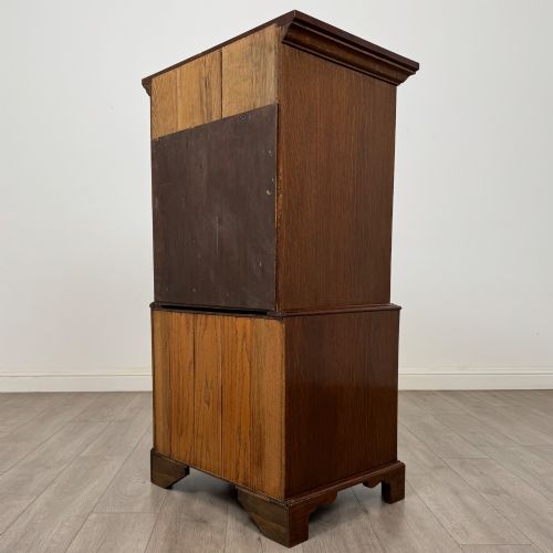 fig 6. A tall early 20th-century oak chest on chest featuring multiple drawers with crossbanded borders and brass drop handles set on bracket feet.