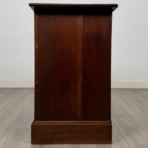fig 2. An antique Edwardian dark oak chest of drawers featuring two small top drawers above two full-width drawers with brass handles.