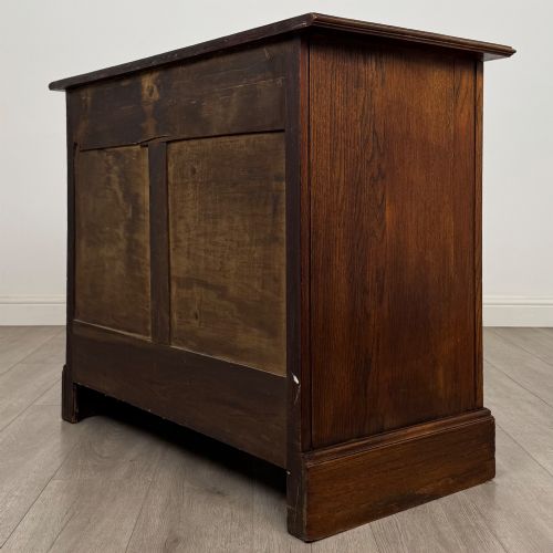 fig 5. An antique Edwardian dark oak chest of drawers featuring two small top drawers above two full-width drawers with brass handles.