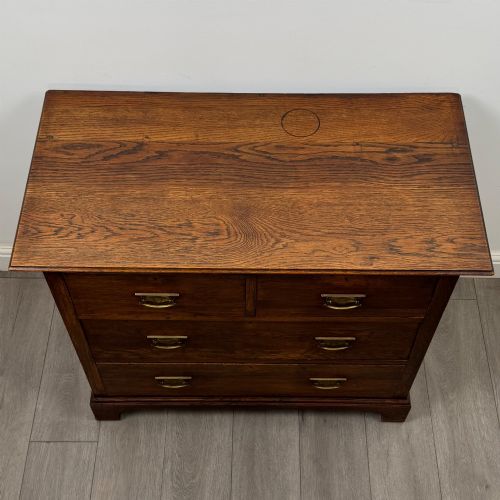 fig 8. An antique Edwardian dark oak chest of drawers featuring two small top drawers above two full-width drawers with brass handles.