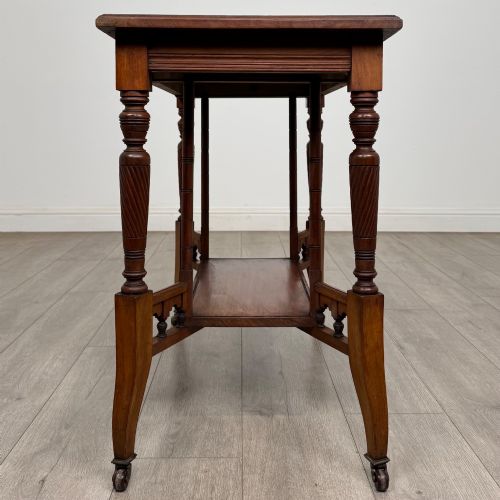 fig 2. An Edwardian walnut side table featuring turned spiral legs, a lower shelf, carved corner brackets, and metal castors.
