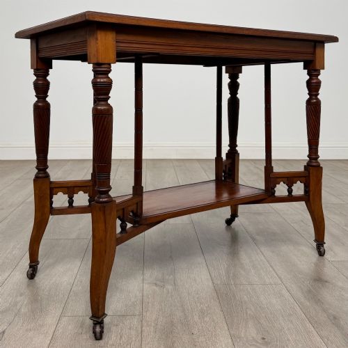 fig 3. An Edwardian walnut side table featuring turned spiral legs, a lower shelf, carved corner brackets, and metal castors.