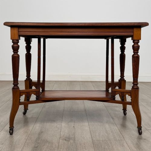 fig 4. An Edwardian walnut side table featuring turned spiral legs, a lower shelf, carved corner brackets, and metal castors.