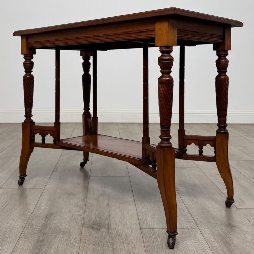 fig 5. An Edwardian walnut side table featuring turned spiral legs, a lower shelf, carved corner brackets, and metal castors.