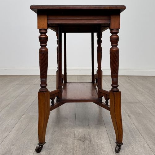 fig 6. An Edwardian walnut side table featuring turned spiral legs, a lower shelf, carved corner brackets, and metal castors.