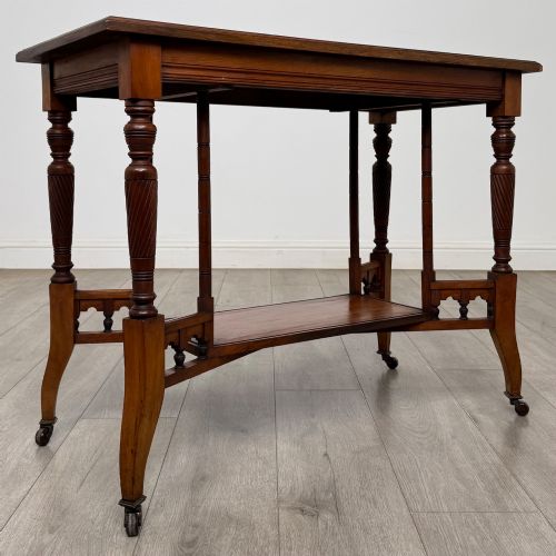 fig 7. An Edwardian walnut side table featuring turned spiral legs, a lower shelf, carved corner brackets, and metal castors.