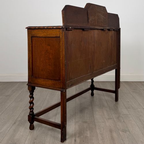 fig 4. An Edwardian golden oak sideboard featuring a raised mirror back gallery, two drawers, two cabinet doors with geometric mouldings, and barley twist front legs.