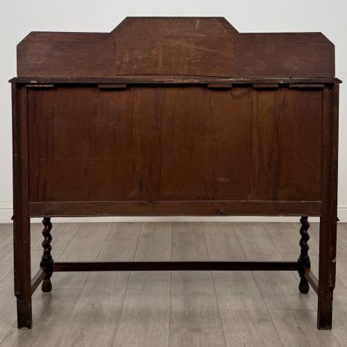 fig 5. An Edwardian golden oak sideboard featuring a raised mirror back gallery, two drawers, two cabinet doors with geometric mouldings, and barley twist front legs.