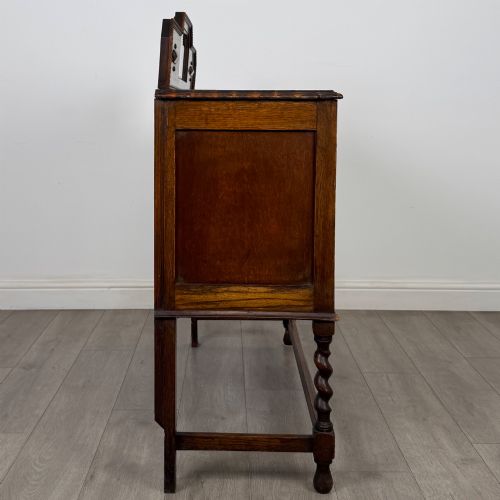 fig 7. An Edwardian golden oak sideboard featuring a raised mirror back gallery, two drawers, two cabinet doors with geometric mouldings, and barley twist front legs.