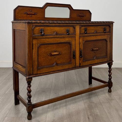 fig 8. An Edwardian golden oak sideboard featuring a raised mirror back gallery, two drawers, two cabinet doors with geometric mouldings, and barley twist front legs.