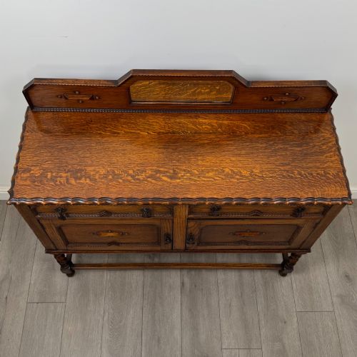 fig 9. An Edwardian golden oak sideboard featuring a raised mirror back gallery, two drawers, two cabinet doors with geometric mouldings, and barley twist front legs.