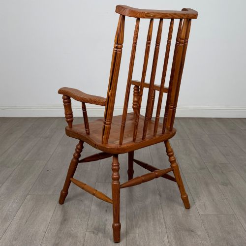 fig 2. A twentieth-century pitch pine armchair featuring a tall stick back, sculpted armrests, and turned legs joined by stretchers.