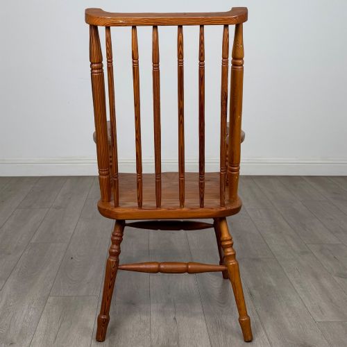 fig 3. A twentieth-century pitch pine armchair featuring a tall stick back, sculpted armrests, and turned legs joined by stretchers.