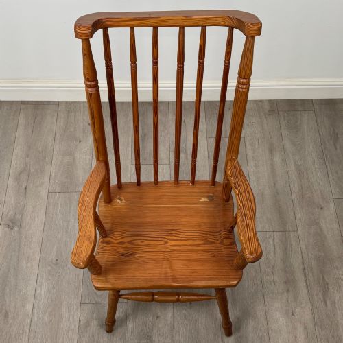 fig 8. A twentieth-century pitch pine armchair featuring a tall stick back, sculpted armrests, and turned legs joined by stretchers.