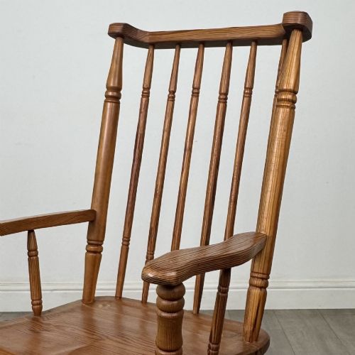 fig 9. A twentieth-century pitch pine armchair featuring a tall stick back, sculpted armrests, and turned legs joined by stretchers.