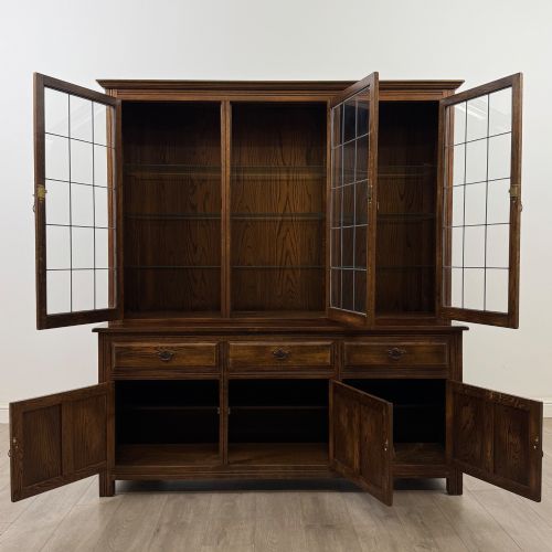 fig 1. A large dark oak display cabinet featuring three leaded glass doors above three drawers and three panelled cupboard doors.