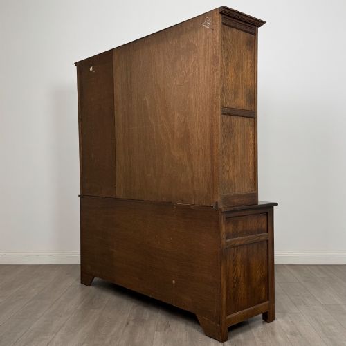 fig 6. A large dark oak display cabinet featuring three leaded glass doors above three drawers and three panelled cupboard doors.