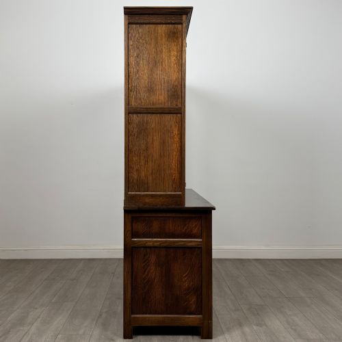 fig 7. A large dark oak display cabinet featuring three leaded glass doors above three drawers and three panelled cupboard doors.