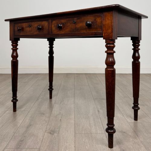 fig 1. A Victorian dark mahogany writing table with two drawers, turned wooden knob handles, keyhole escutcheons, and four turned legs.