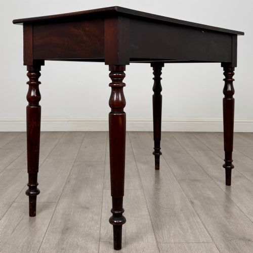 fig 3. A Victorian dark mahogany writing table with two drawers, turned wooden knob handles, keyhole escutcheons, and four turned legs.