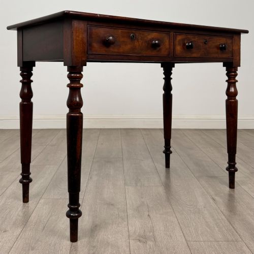 fig 7. A Victorian dark mahogany writing table with two drawers, turned wooden knob handles, keyhole escutcheons, and four turned legs.