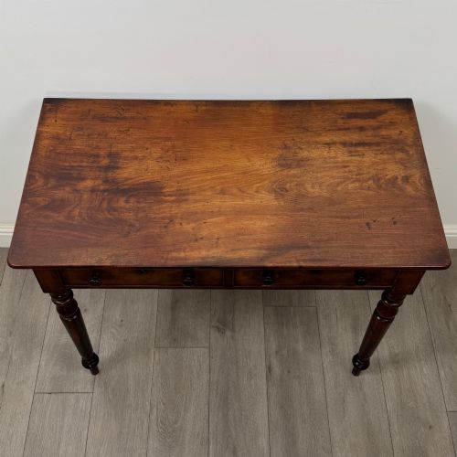 fig 8. A Victorian dark mahogany writing table with two drawers, turned wooden knob handles, keyhole escutcheons, and four turned legs.