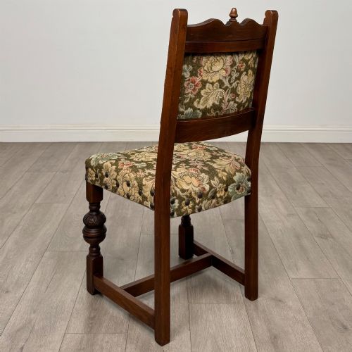 fig 3. A set of six dark oak dining chairs with carved crest rails, floral tapestry upholstered backrests and seats, and turned front legs.