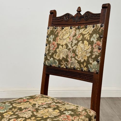 fig 4. A set of six dark oak dining chairs with carved crest rails, floral tapestry upholstered backrests and seats, and turned front legs.