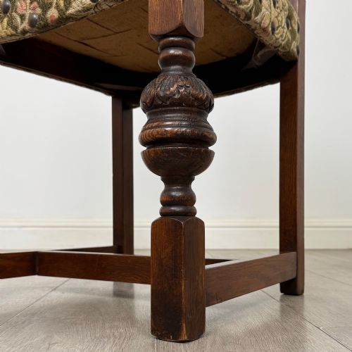 fig 6. A set of six dark oak dining chairs with carved crest rails, floral tapestry upholstered backrests and seats, and turned front legs.